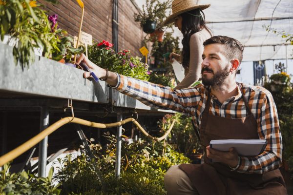 jovenes-jardineros-rociando-plantas-tomando-notas